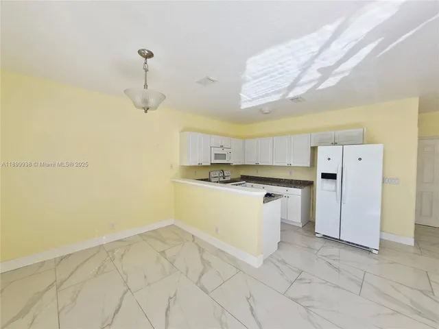 a kitchen with a refrigerator and white cabinets