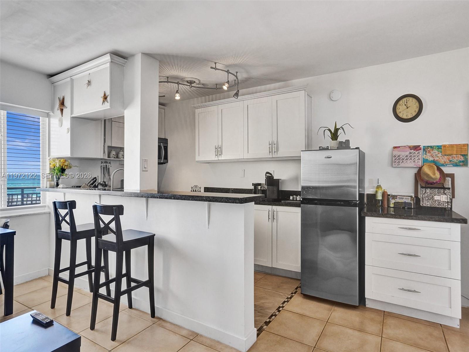 1815 North Surf Road, Unit 202 Hollywood, FL 33019 - Photo 6 of 32 a kitchen with a table chairs microwave and cabinets