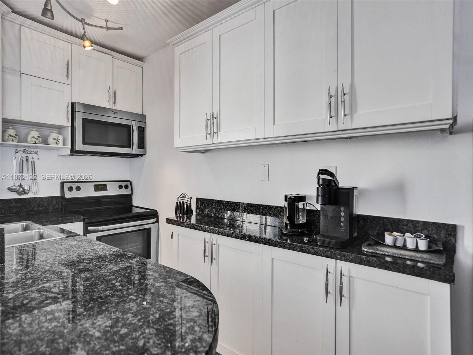 1815 North Surf Road, Unit 202 Hollywood, FL 33019 - Photo 7 of 32 a kitchen with stainless steel appliances granite countertop white cabinets sink and dishwasher