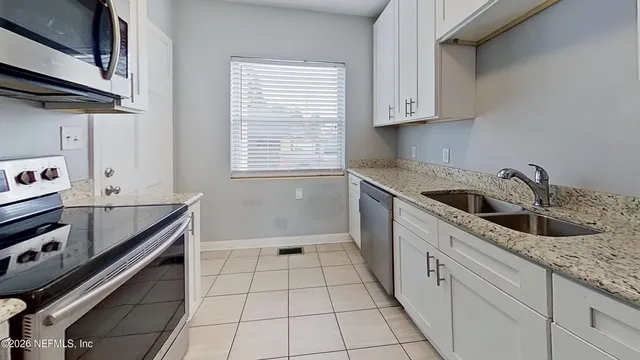 a kitchen with granite countertop a sink a stove and cabinets