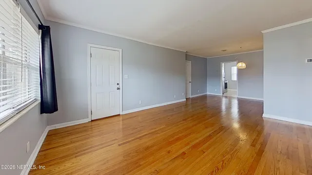 a view of empty room with wooden floor and fan