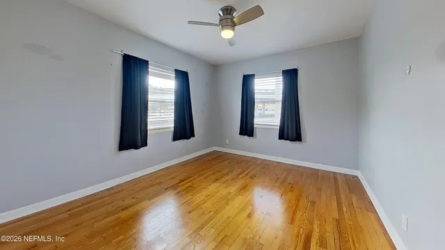a view of an empty room with a window and wooden floor