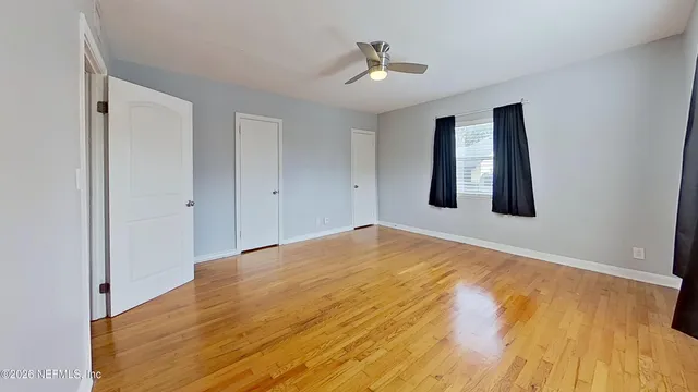 a view of a room with wooden floor and ceiling fan