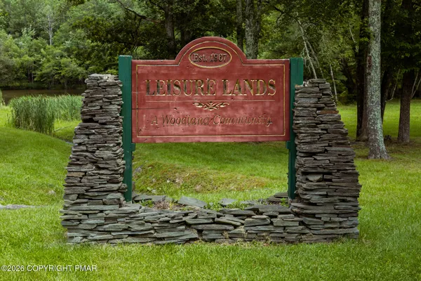 a sign of golf club on a wall under a tree