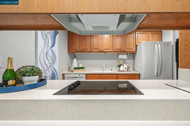 a white kitchen with a sink a refrigerator and a window