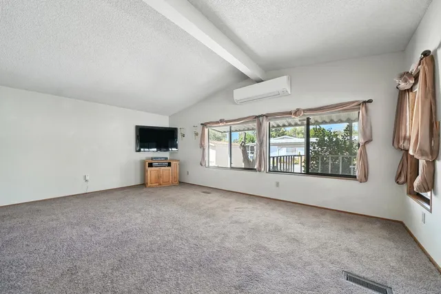 an empty room with chandelier fan and windows