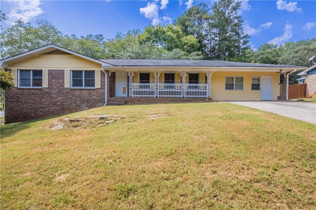 a front view of house with yard and trees in the background