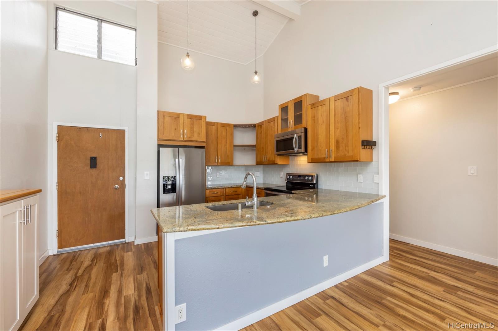a kitchen with stainless steel appliances granite countertop a sink a refrigerator and a wooden floor