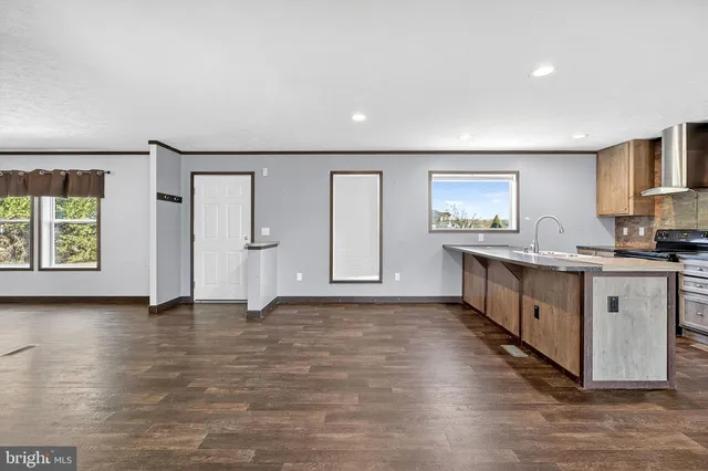 a large white kitchen with a sink and dishwasher with wooden floor