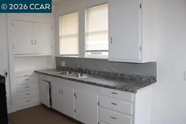 a kitchen with granite countertop white cabinets and a sink