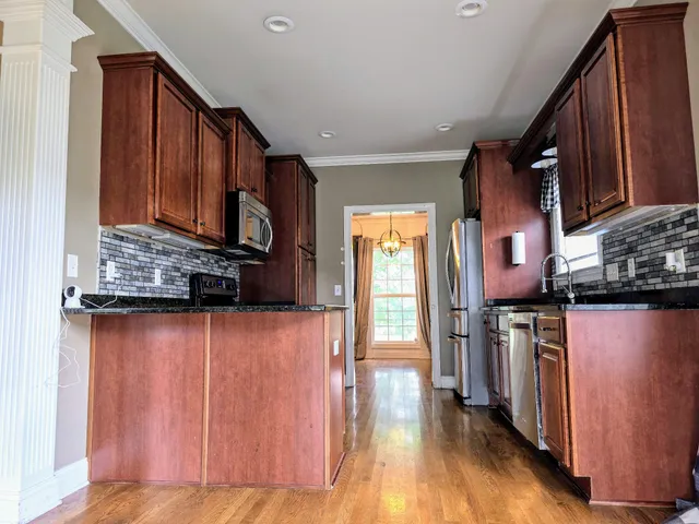 a kitchen with stainless steel appliances granite countertop a refrigerator a stove and a wooden floors