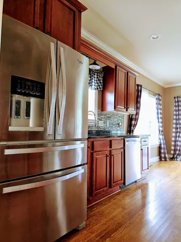a view of an empty room with wooden floor and windows