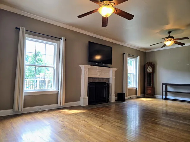 a view of an empty room with wooden floor fireplace and a window