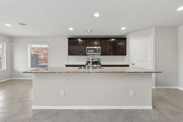 a kitchen with stainless steel appliances granite countertop a sink a stove and a refrigerator