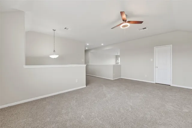 an empty room with chandelier fan and windows