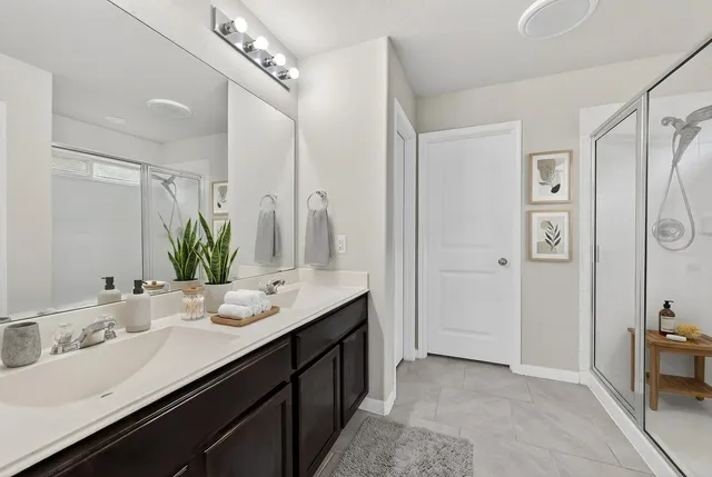 a bathroom with a double vanity sink a mirror and a shower
