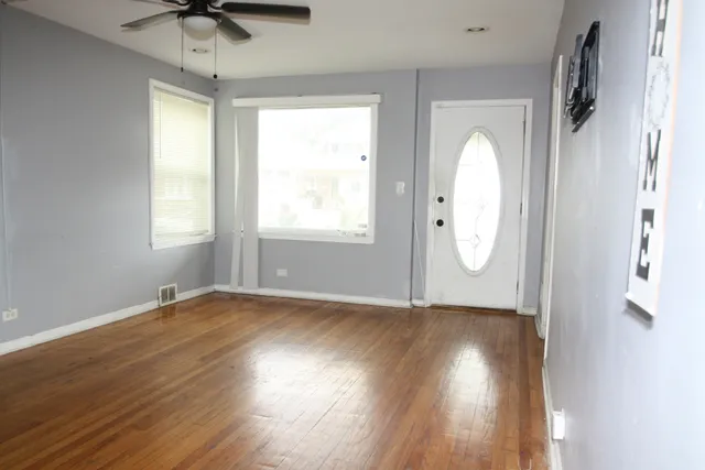 an empty room with wooden floor and windows