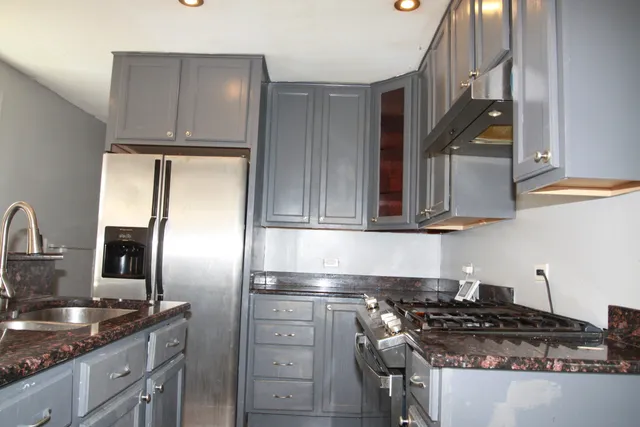 a kitchen with stainless steel appliances granite countertop a stove a sink and a refrigerator