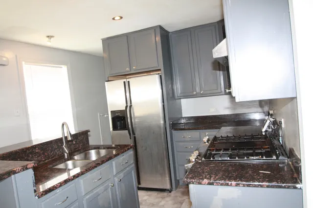 a kitchen with granite countertop a refrigerator stove and sink