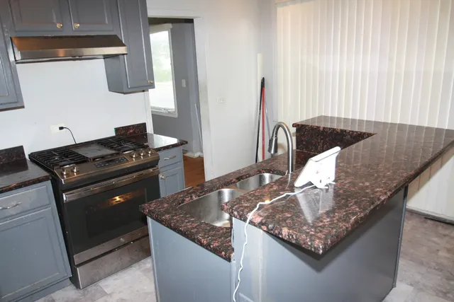 a kitchen with granite countertop a sink dishwasher stove and cabinets