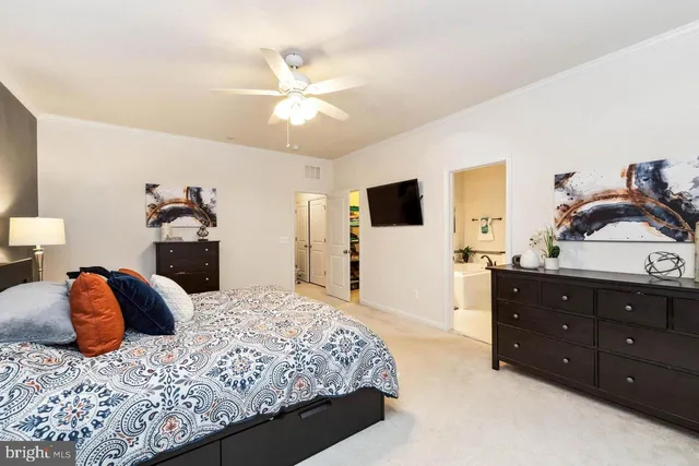a bedroom with a large bed and a flat tv screen on dresser