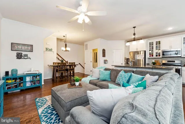 a living room with furniture kitchen view and a wooden floor