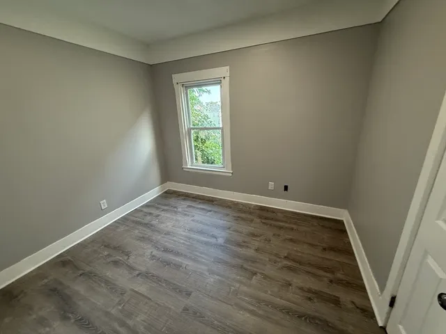 an empty room with wooden floor and window