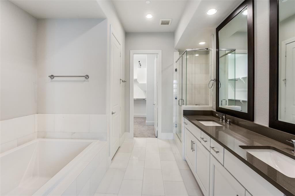 5421 Patterson Street Irving, TX 75039 - Photo 16 of 32 Spacious bathroom featuring a double vanity with undermount sinks, a glass-enclosed shower, a built-in bathtub with tiled surround, recessed lighting, and white tile flooring