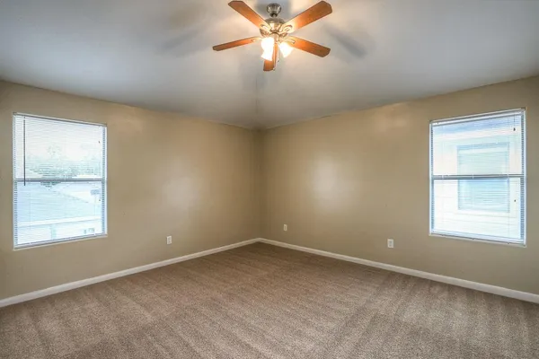 an empty room with a window and a fan