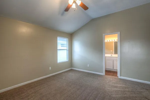 an empty room with a chandelier fan and windows