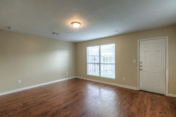 an empty room with wooden floor and windows