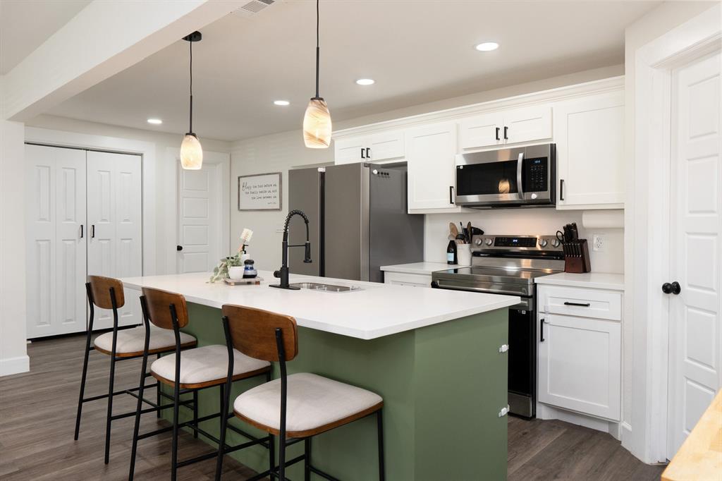205 Oregon Avenue Azle, TX 76020 - Photo 15 of 40 Kitchen with white cabinets, hanging light fixtures, and an island with sink