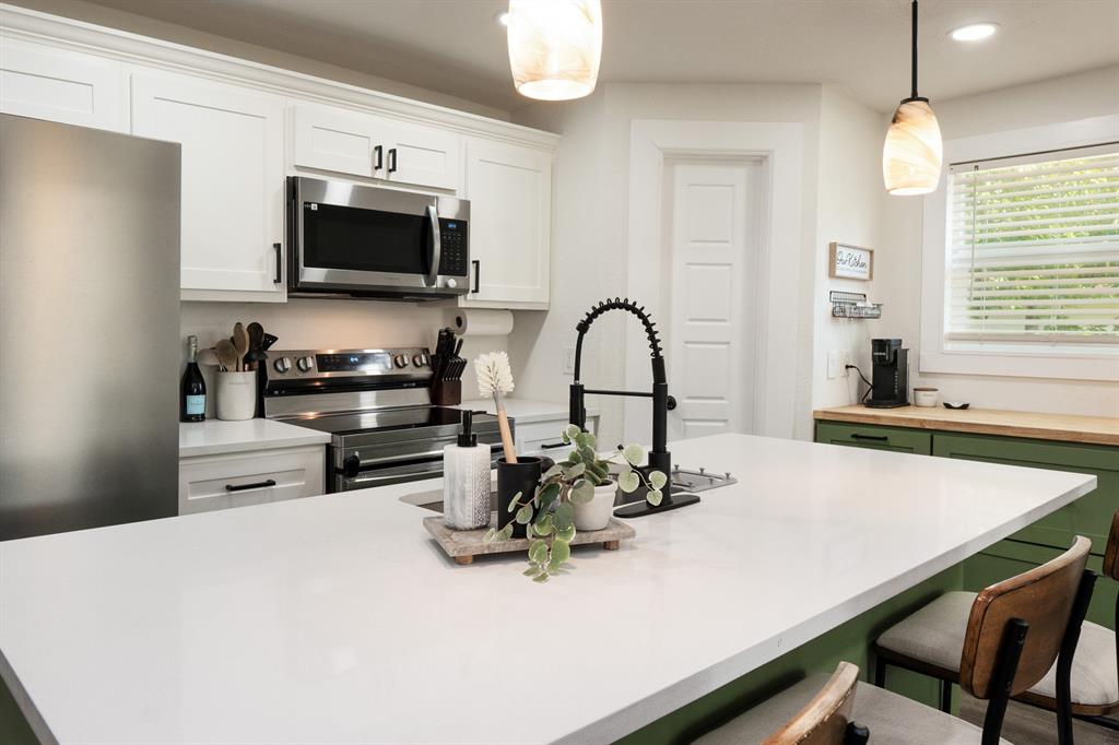 205 Oregon Avenue Azle, TX 76020 - Photo 16 of 40 Kitchen with pendant lighting, a kitchen breakfast bar, green cabinets, and white cabinetry