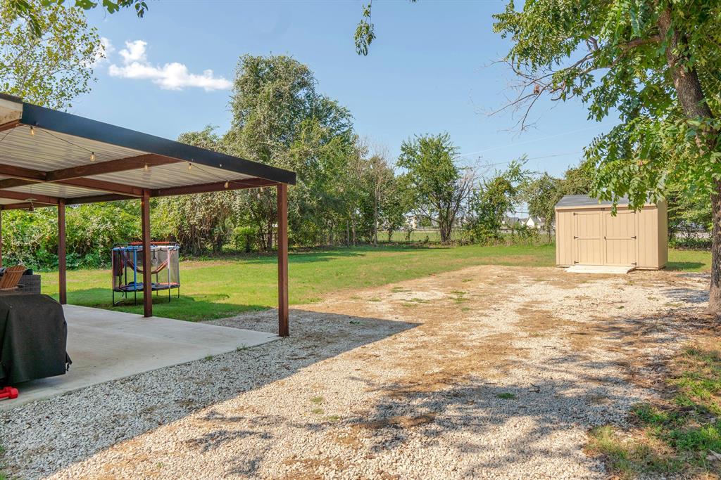 205 Oregon Avenue Azle, TX 76020 - Photo 31 of 40 View of grassy yard featuring a storage shed