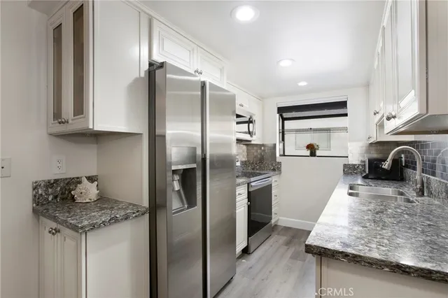 a kitchen with stainless steel appliances granite countertop a sink a stove and a refrigerator
