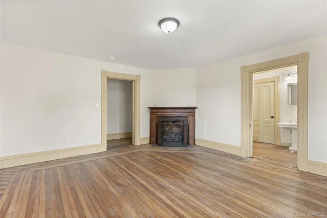 an empty room with wooden floor and fireplace