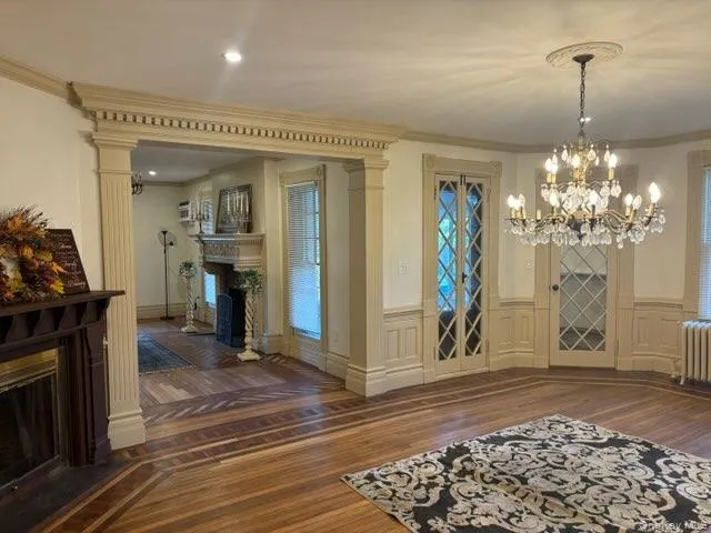 a view of a livingroom with furniture wooden floor fireplace and chandelier