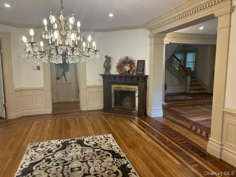 a view of a livingroom with a fireplace wooden floor and chandelier