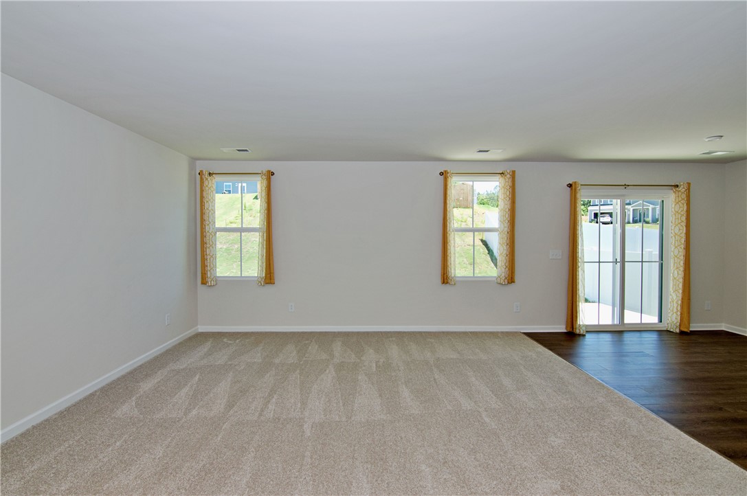 723 Peridot Way Westminster, SC 29693 - Photo 13 of 45 Natural light streams into this expansive open-concept space, featuring plush carpeting and rich wood-look flooring.