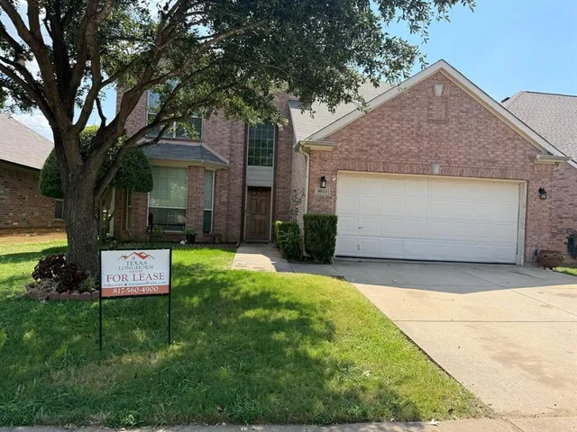 a sign board with a yard and large trees