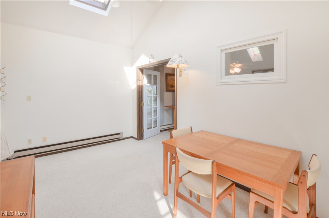 3120 West Elmore Road Port Clinton, OH 43452 - Photo 10 of 27 Dining room with a high ceiling, light carpet, a baseboard radiator, and lofted ceiling with skylight