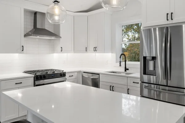 a kitchen with stainless steel appliances a stove a sink and white cabinets
