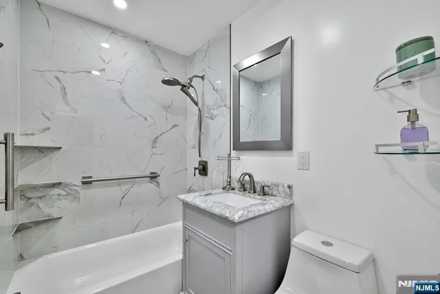 a bathroom with a granite countertop sink a toilet and shower