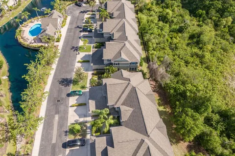 an aerial view of a house with swimming pool and large trees