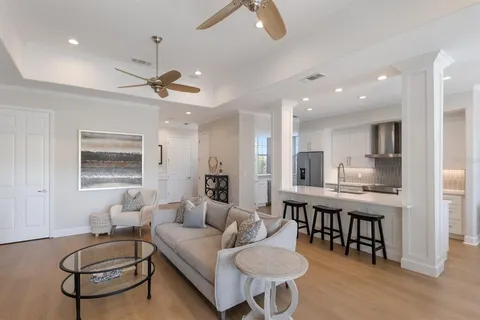 a living room with furniture kitchen view and a chandelier