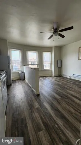 a kitchen with stainless steel appliances wooden floor and living room view