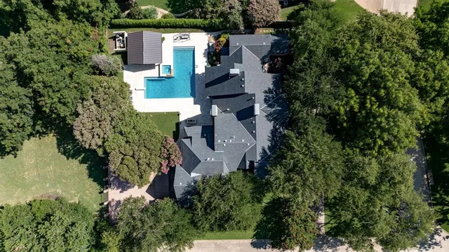 an aerial view of a house with a yard and trees all around