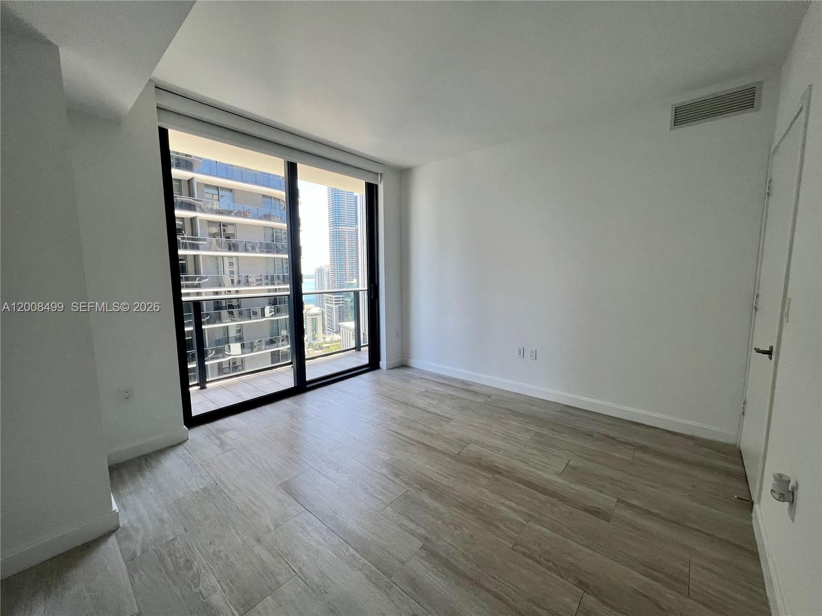 55 Southwest 9th Street, Unit 2702 Miami, FL 33130 - Photo 13 of 36 a view of an empty room with wooden floor and a window