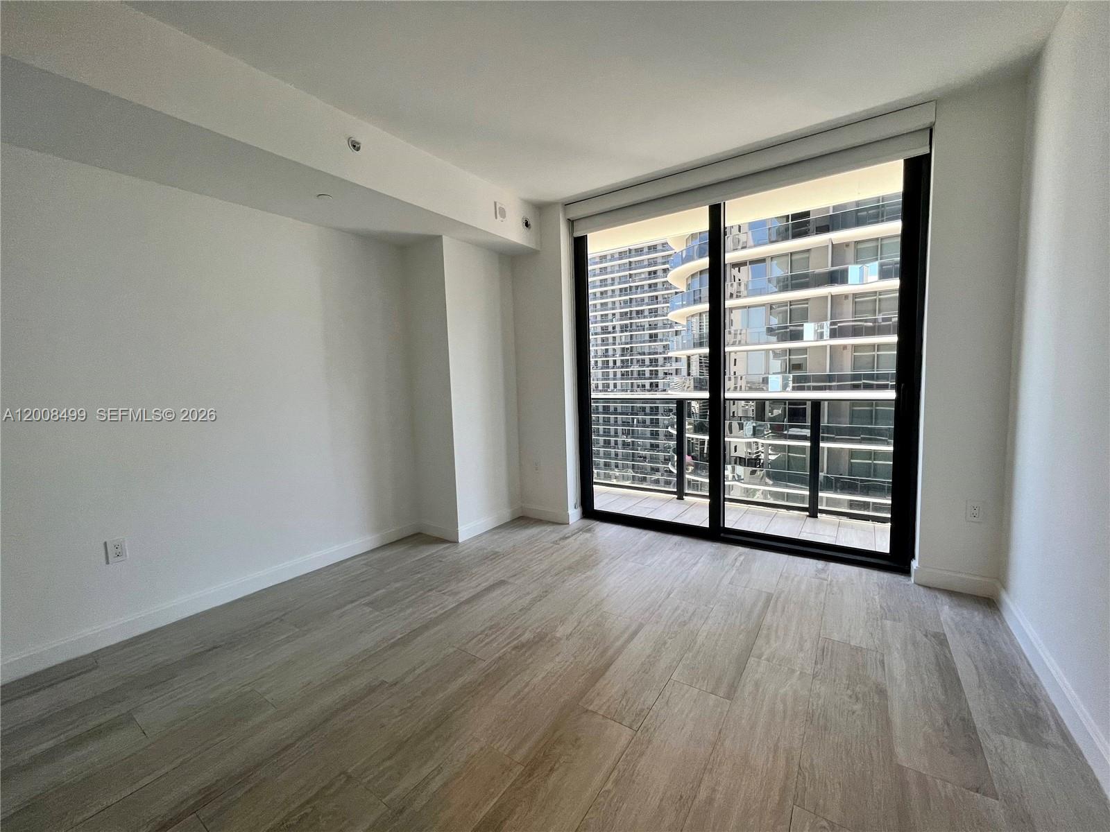 55 Southwest 9th Street, Unit 2702 Miami, FL 33130 - Photo 3 of 36 a view of an empty room with wooden floor and a window