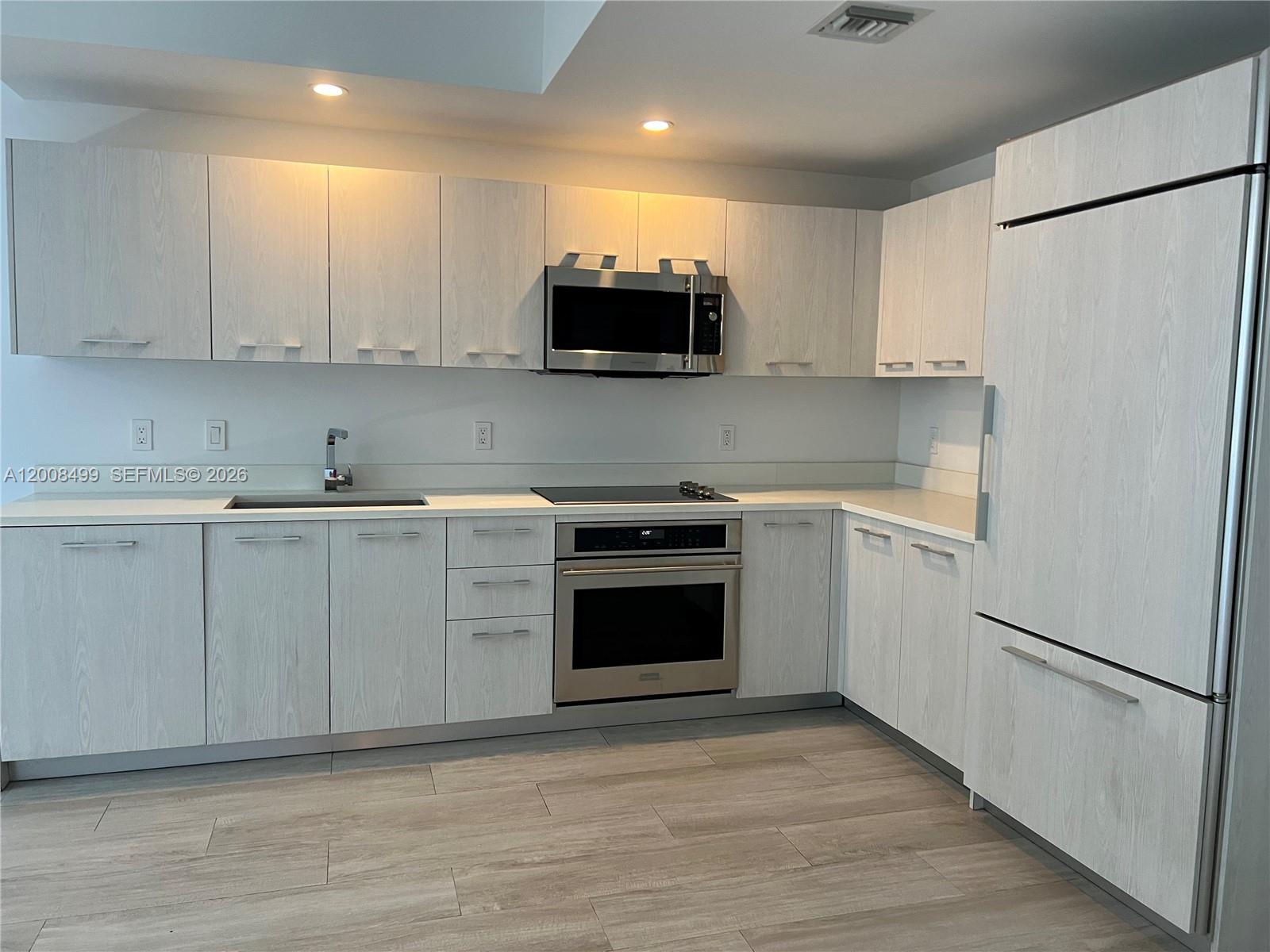 55 Southwest 9th Street, Unit 2702 Miami, FL 33130 - Photo 4 of 36 a kitchen with white cabinets and white appliances